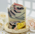 Artisan Love Spell handmade soap bar with pink, black, and cream swirl pattern, surrounded by soft white roses.