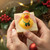 Handcrafted kids’ soap with Christmas rubber duck in Santa hat, held in hands amid holiday greenery; festive bath-time gift idea.
