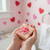 Child holding a handmade Valentine’s Day kids’ soap bar with pink swirls and a rubber duck toy, in a heart-themed bathroom.