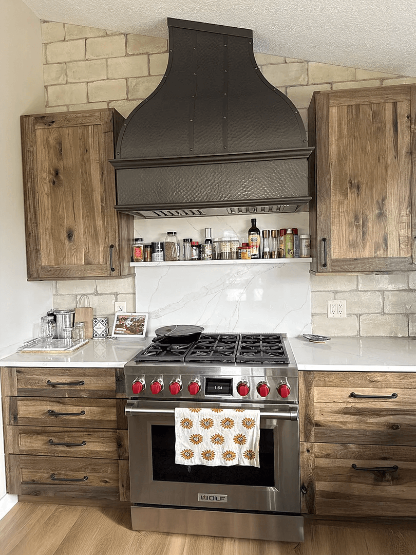 stainless steel custom range hood with brass trims in a white kitchen
