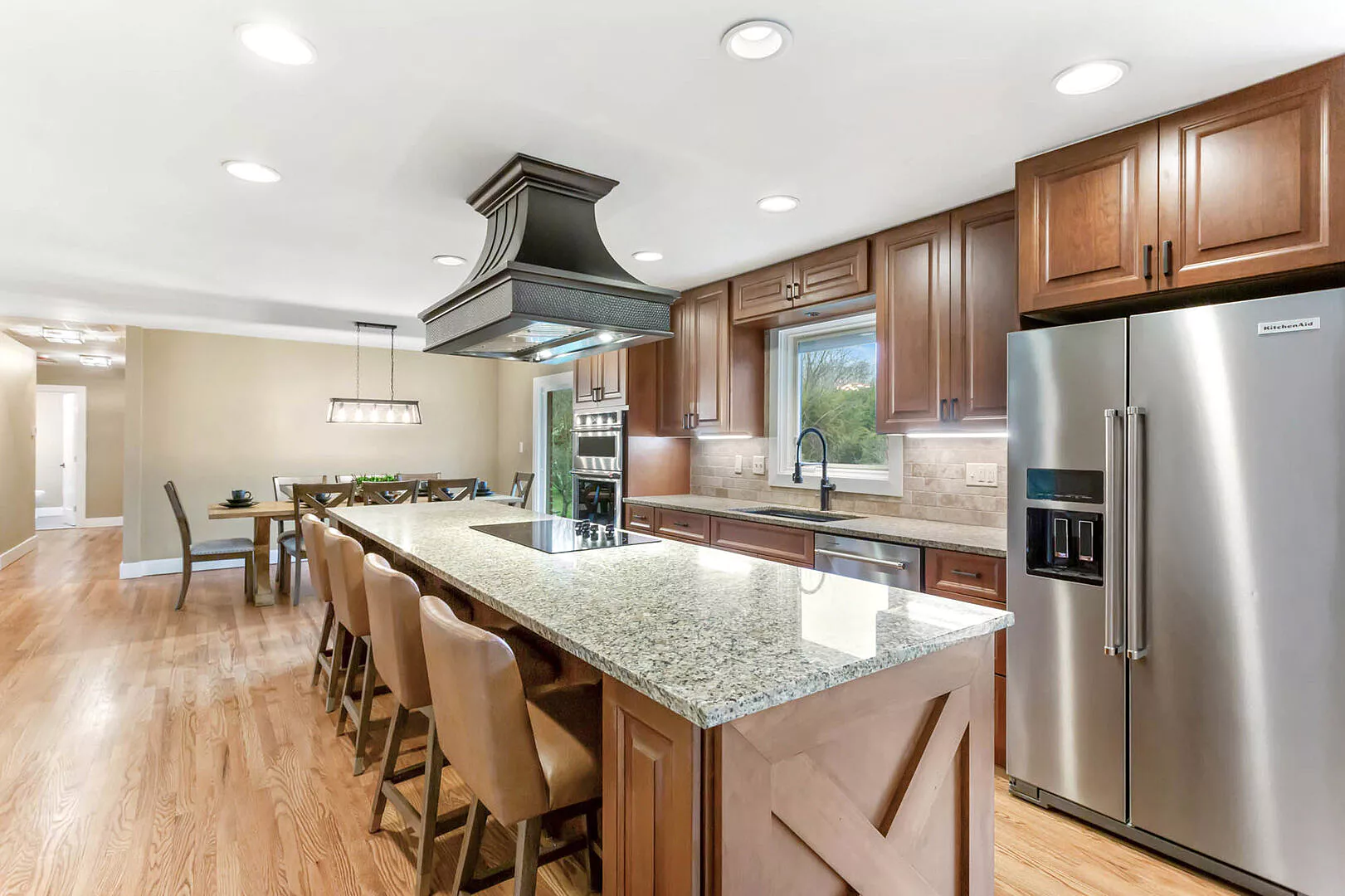 stainless steel custom range hood with brass trims in a white kitchen