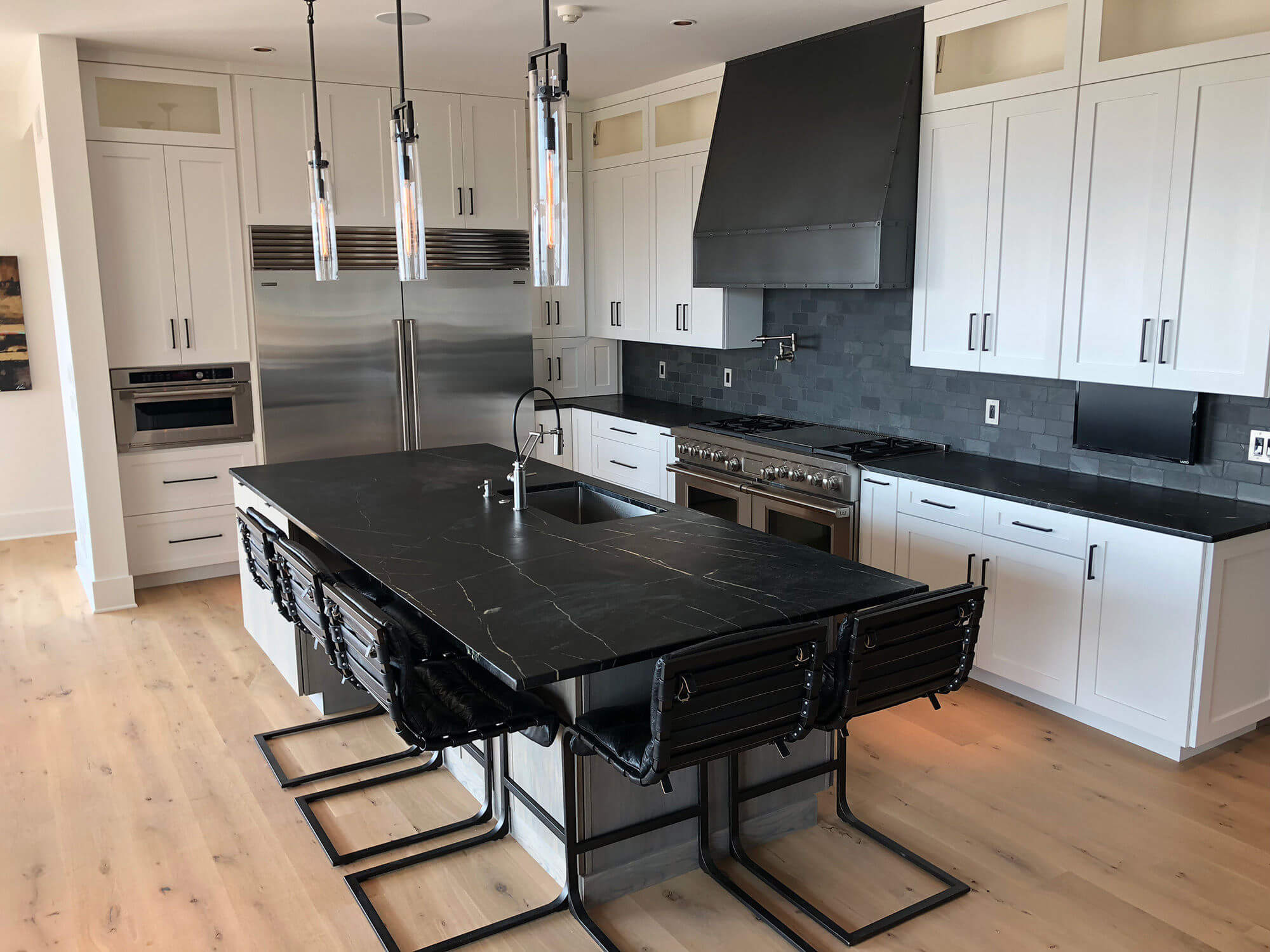stainless steel custom range hood with brass trims in a white kitchen