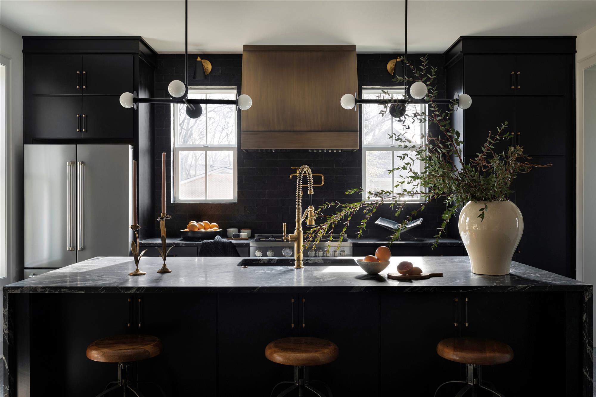 stainless steel custom range hood with brass trims in a white kitchen