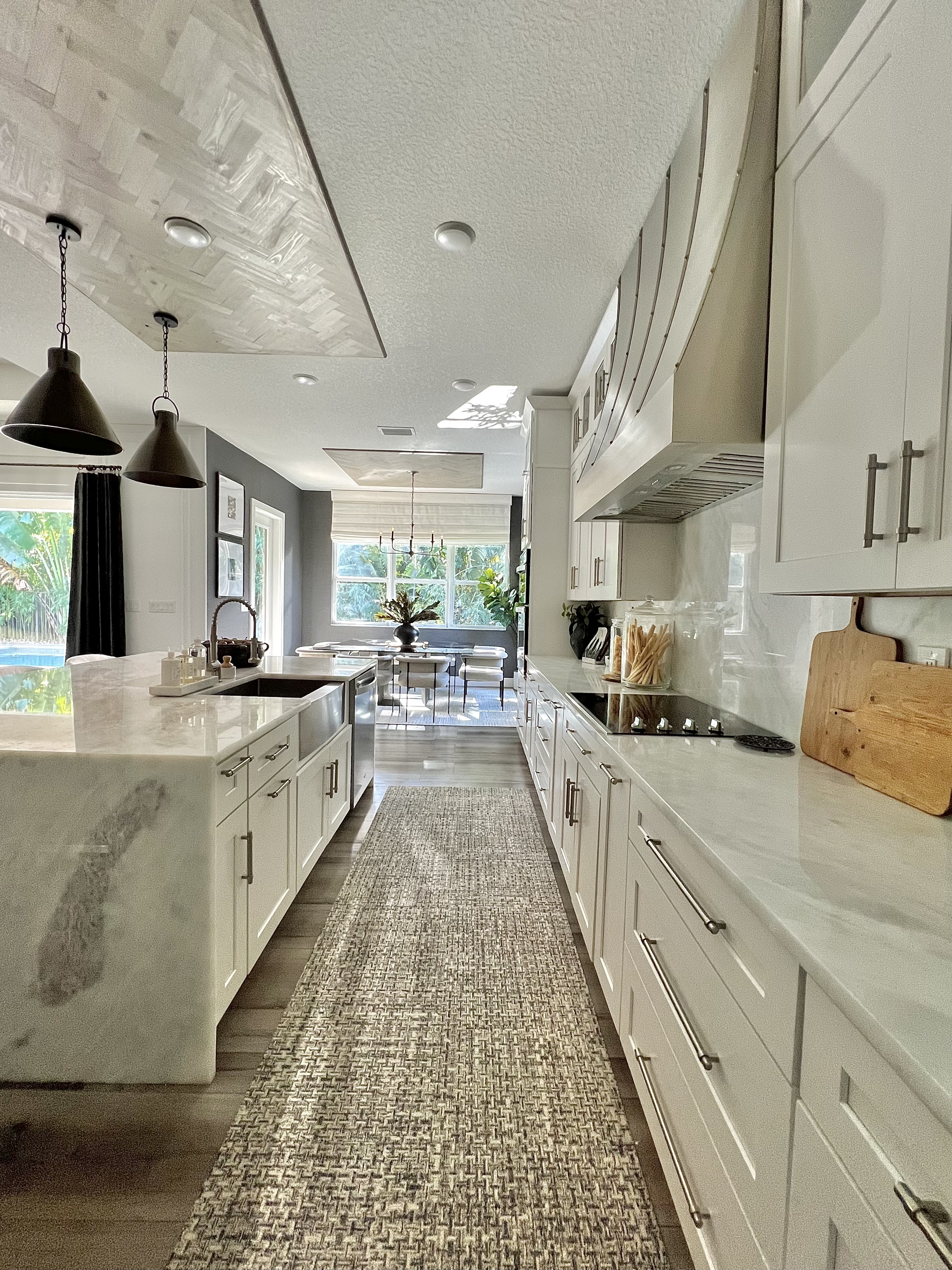 stainless steel custom range hood with brass trims in a white kitchen