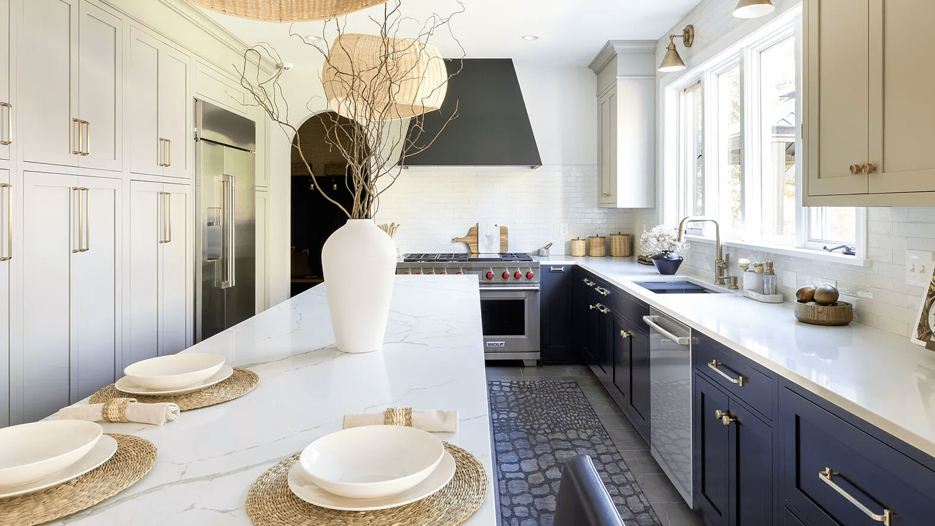 stainless steel custom range hood with brass trims in a white kitchen