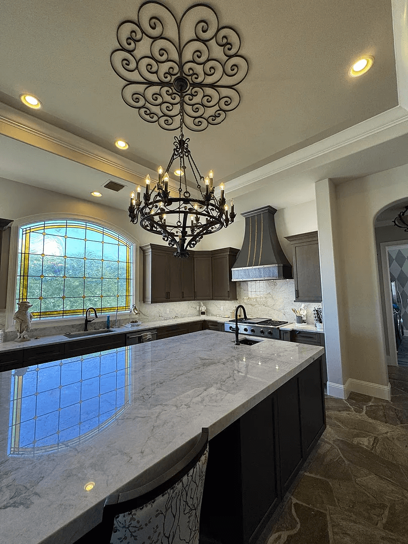 stainless steel custom range hood with brass trims in a white kitchen