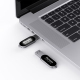 A silver Olympia LED flash drive is plugged into a laptop's USB port, with another flash drive beside it.