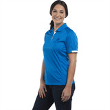 A women's short sleeve polo in bright blue, featuring a logo, worn by a smiling model against a white background.