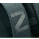 A close-up of the padded strap of a dark green laptop backpack featuring a simple logo.