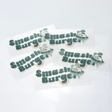 A collection of green and white stickers featuring a playful logo and branding for "Smash Burger."
