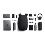 A black Bellroy Via Backpack 20L surrounded by a laptop, drink bottle, sunglasses, and various accessories.