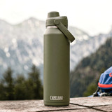 A drink bottle in olive green with a screw-top lid and a handle, featuring a logo. Set against a mountainous background.