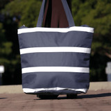 A navy insulated cooler bag with white stripes, featuring sturdy handles and a branding logo.