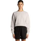 A cropped, light grey jumper with a relaxed fit, paired with black shorts. The model stands with arms by her side.