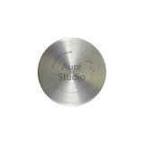 A stainless steel circular plate with a minimalist design featuring the words "Auré Studio" and a decorative leaf motif.