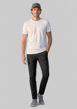 A man wearing black Venture Pants and a white t-shirt, with a grey cap and shoes, standing against a plain background.