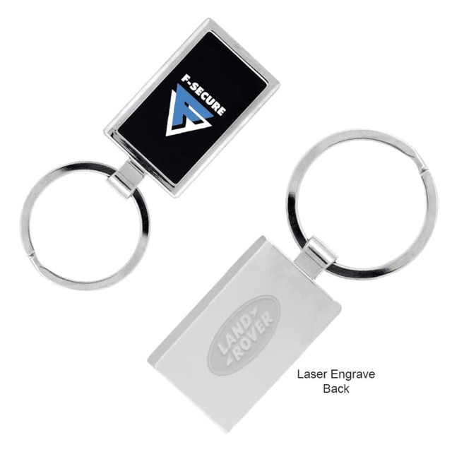 A silver keychain featuring a rectangular design with a logo, suitable for engraving on the back.