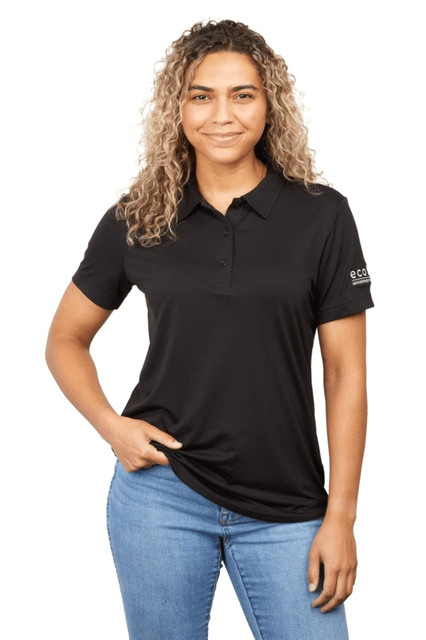A woman wearing a black eco-friendly polo shirt, featuring a logo on the sleeve and styled with jeans.