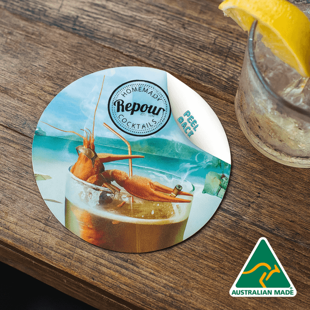 A round, colourful coaster featuring a cocktail and seafood, with an Australian made logo in one corner.