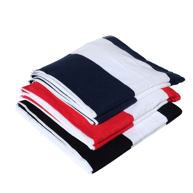 A stack of cotton beach towels featuring navy, red, white, and black stripes, with one towel having a logo.