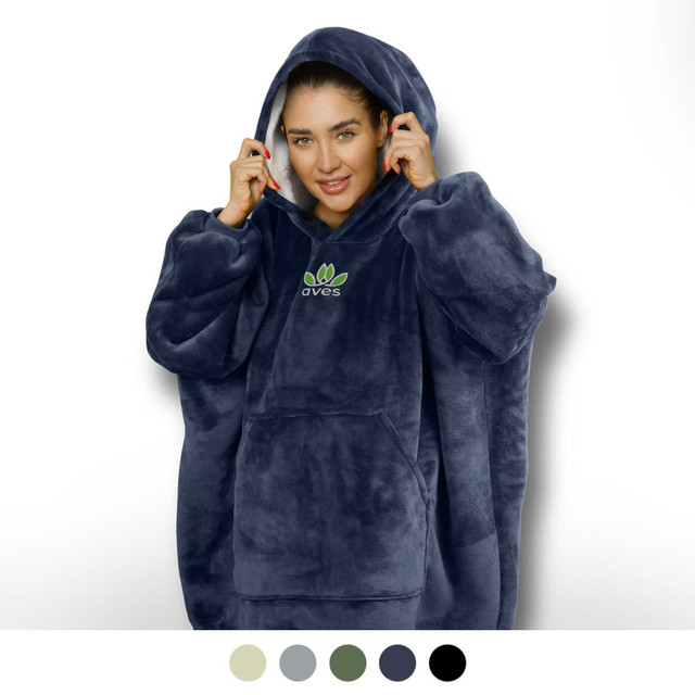 A woman wearing a navy blue hoodie blanket with a large hood and a front pocket, featuring a logo.