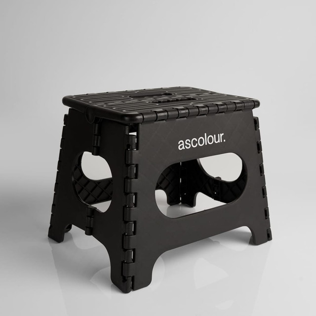 A black ASC Utility Stool with a textured surface and cut-out handles, featuring a logo on one side.