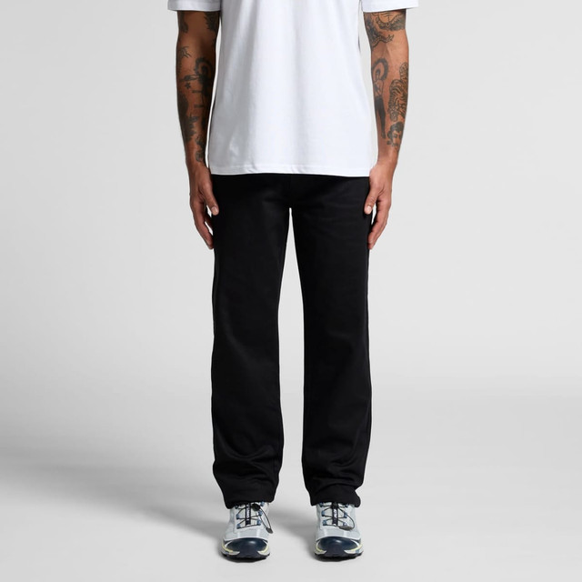 Relaxed black pants displayed on a person standing with hands by their sides, wearing a white t-shirt and sneakers.