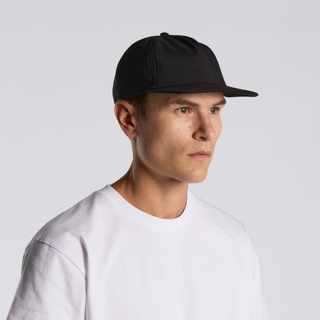 A black cap with a flat brim, worn by a model in a white t-shirt, featuring branding on the front.