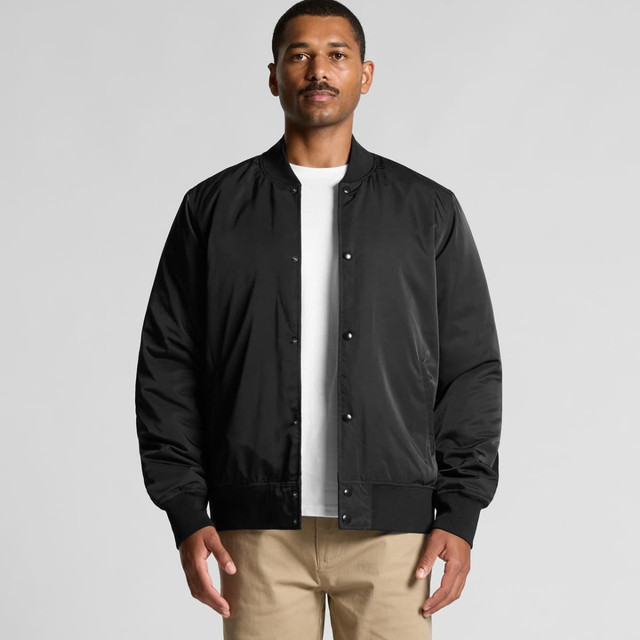 A man wearing a black bomber jacket with a front snap closure and ribbed cuffs, posing against a neutral background.