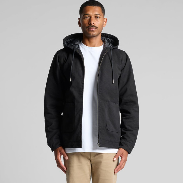 A man wearing a black canvas heavy hooded jacket with zip and front pockets. The jacket has a hood and a grey lining.
