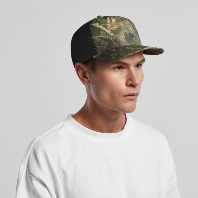 A camo cap featuring a mesh back, in shades of green and brown, worn by a model. The cap includes a logo.