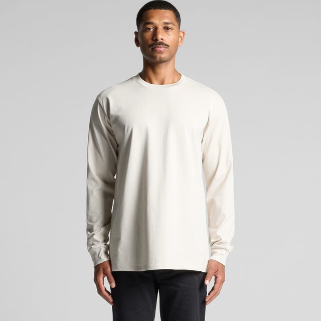 A long-sleeved, cream-coloured t-shirt worn by a man, with a logo visible on the garment.