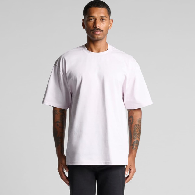 A light pink heavy tee shirt on a person with tattoos, standing against a neutral background.