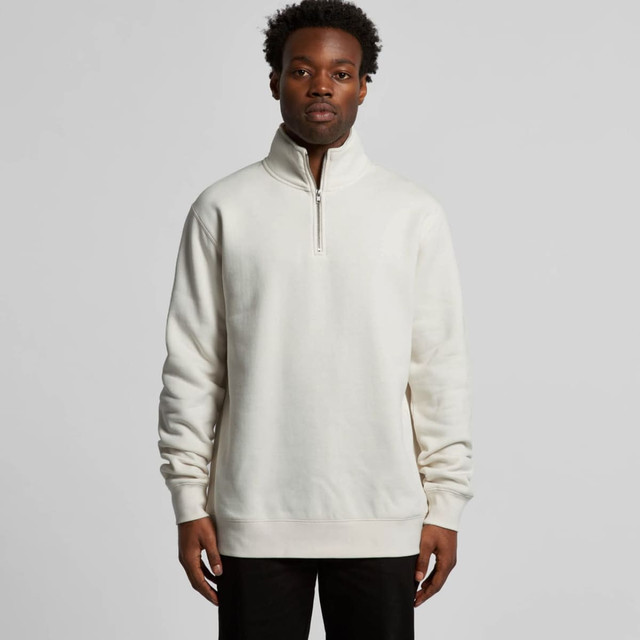 A man is wearing a cream-coloured half zip crew jumper with a relaxed fit, featuring a stand-up collar.