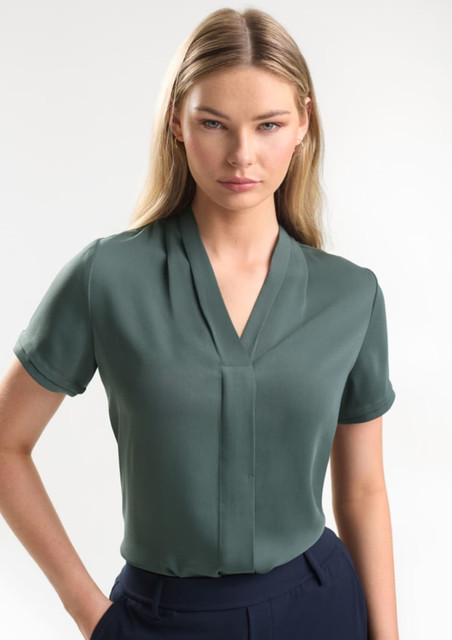 A short-sleeve button-up shirt in a soft green colour, featuring a v-neck design and a subtle front pleat.