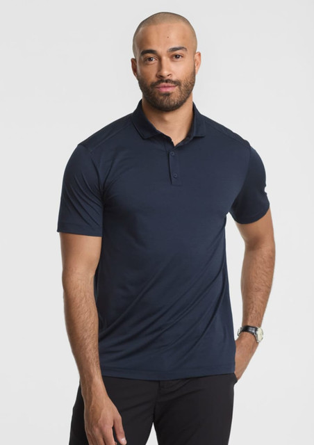 A man stands wearing a navy blue short sleeve polo shirt, featuring a collar and a logo.