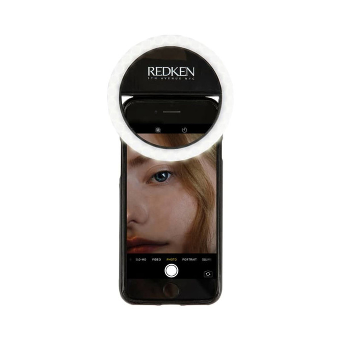 A white Smiley LED selfie light mounted on a smartphone, illuminating a close-up photo of a person's face.