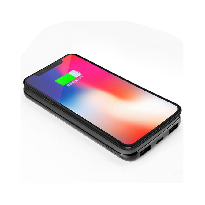 A black wireless power bank with a smartphone on top, displaying a charging indication on the screen.