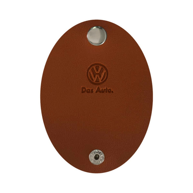 A brown oval-shaped key holder with a metallic button and an embossed logo, featuring the name "Das Auto."