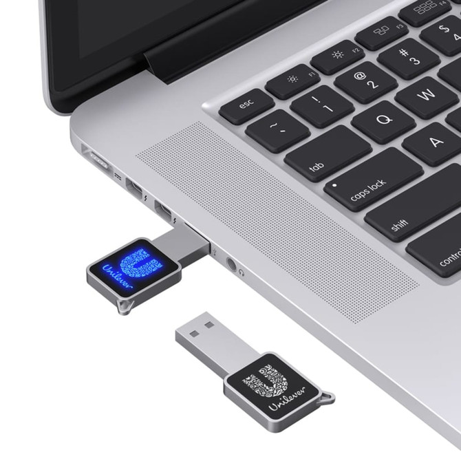 A compact black LED flash drive connected to a silver laptop, featuring a logo on the drive.