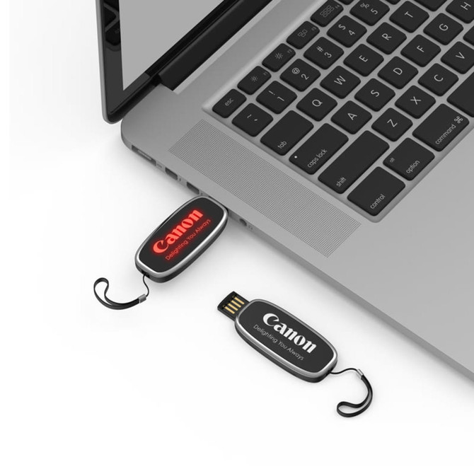 A black and red LED flash drive is connected to a laptop, with a logo visible on the drive.