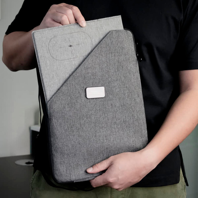 A person holding a grey Evopad Charge Eco Mouse Pad, featuring a textured fabric surface and a logo on the front.