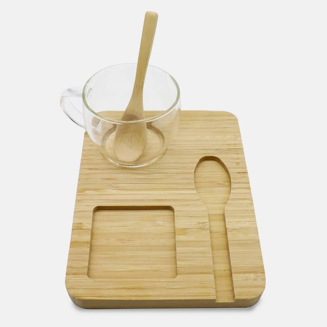 A bamboo tray featuring a glass cup with a wooden spoon, alongside a carved spoon-shaped and square indent.