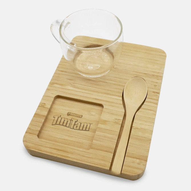 A bamboo tray set featuring a clear glass cup, wooden spoon, and a designated spot for a Tim Tam biscuit.