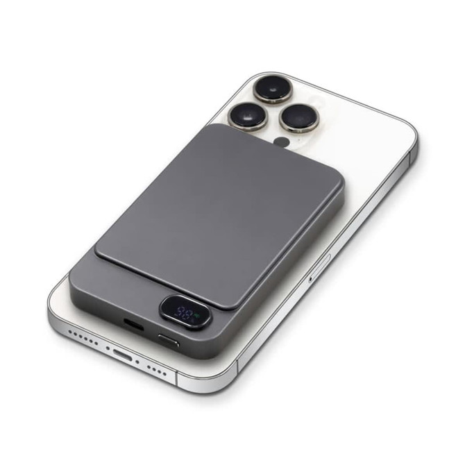 A grey magnetic wireless power bank sits on a smartphone, featuring a sleek design and a logo.