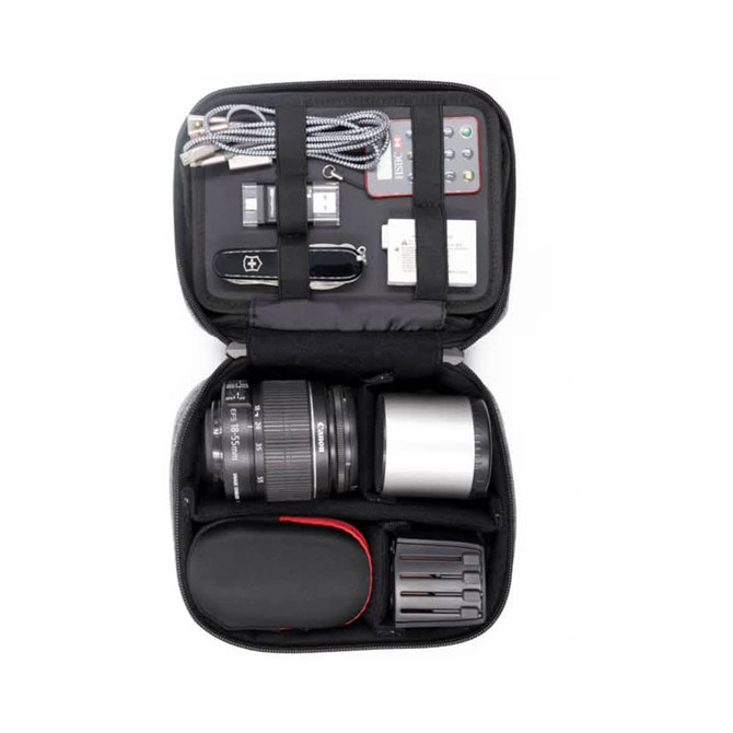 A black accessory case filled with a camera lens, battery packs, cables, a multi-tool, and a memory card.