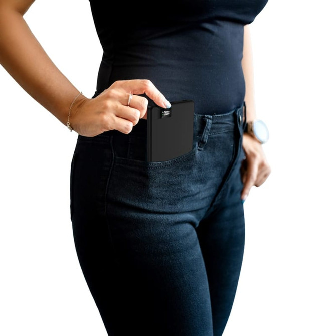 A black 15W MagSafe power bank being pulled from a pocket, featuring a slim design. It has a logo on the surface.