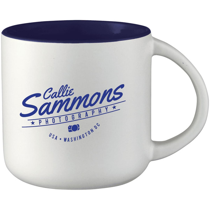 A ceramic coffee mug with a white body and navy blue interior, featuring a logo on one side.