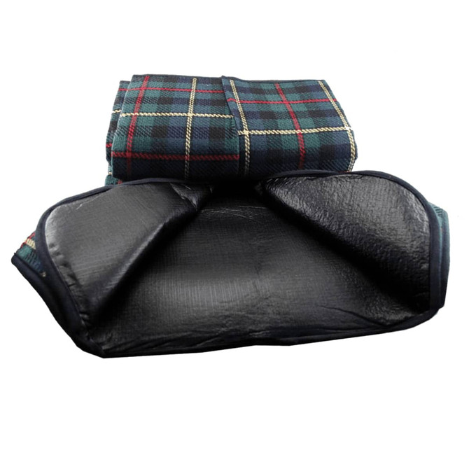 A picnic rug with a checkered pattern in green and navy, featuring a black waterproof backing. It has a logo on the edge.