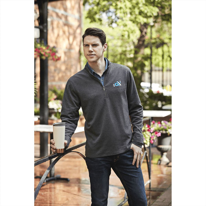 A grey men's quarter zip jumper featuring a branding logo, paired with dark jeans and a coffee cup.
